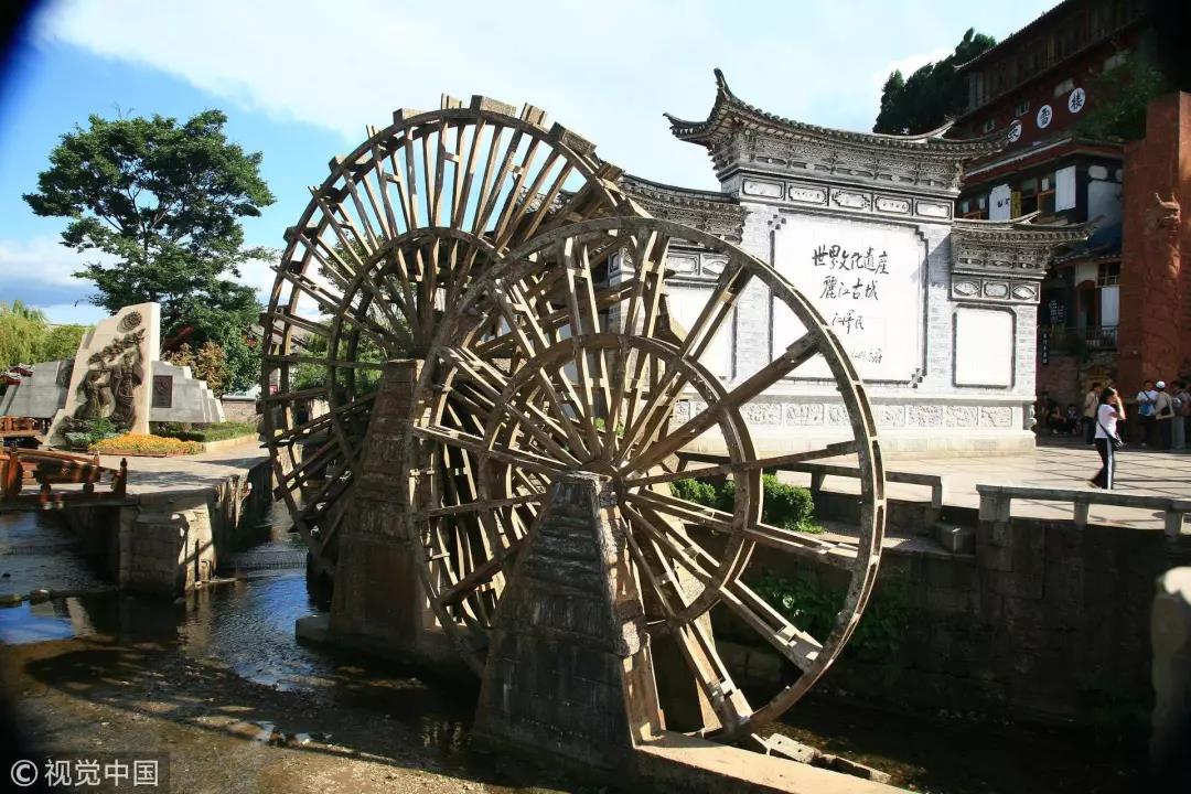2007年6月26日，云南丽江古城，用于摆设拍照的水车和后面“世界文化遗产”的题字 / 视觉中国